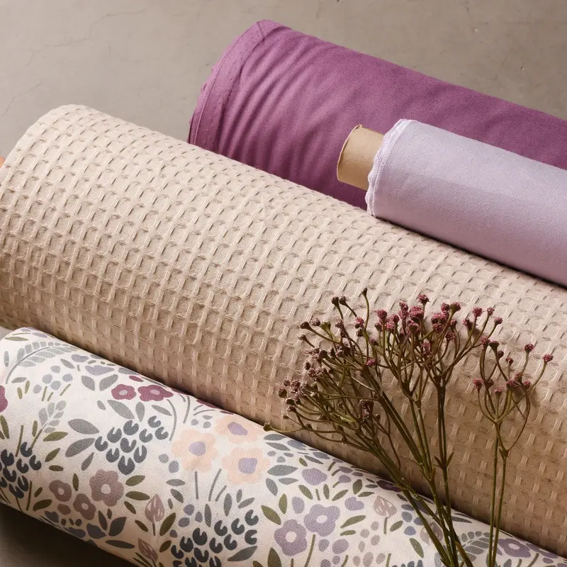 Gerollte Dekostoffe in Beige und Violett mit Waffelstruktur und feinem Blumenmuster