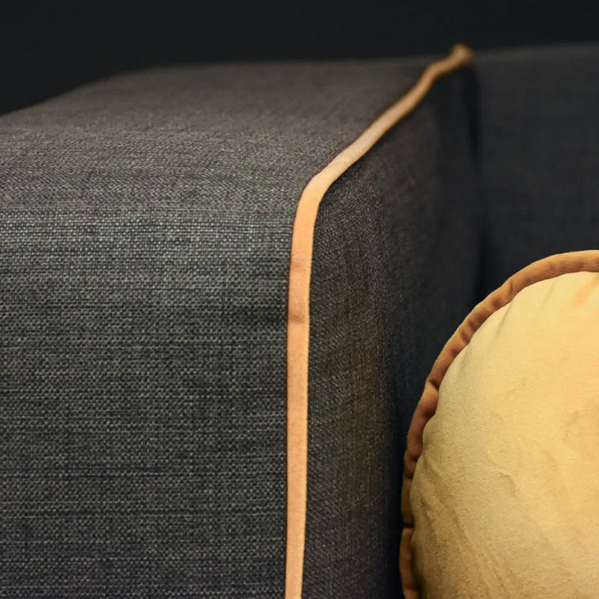 Gelbe Samt-Kissenrolle auf Sofa mit grauem Polsterstoff