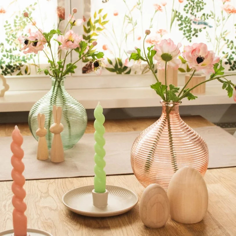 Frühlingshafte Wohnaccessoires: Rillenvasen, Spiralkerzen und Holzdeko auf dem Tisch