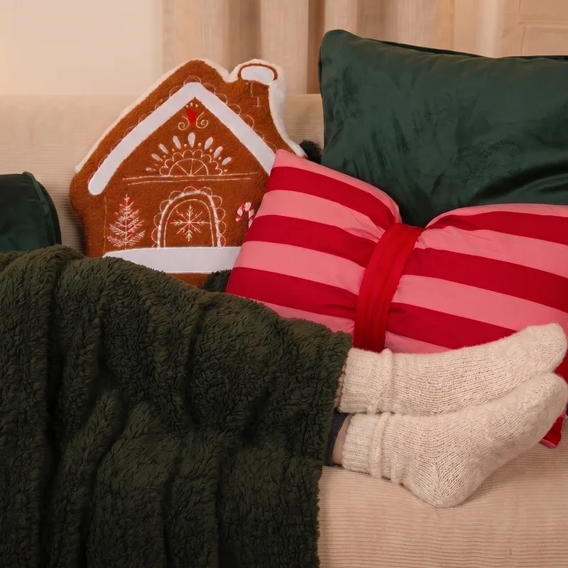 Kuschelige Decke, Wollsocken und Lebkuchenhaus-Kissen als Wohlfühlgeschenk für Frauen