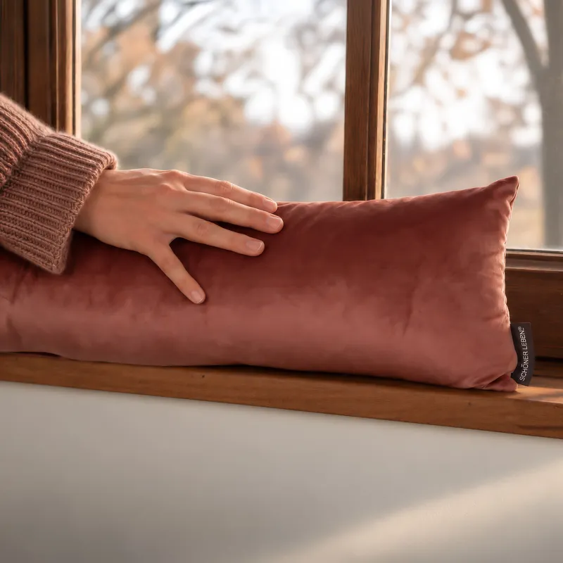 Zugluftstopper aus Samt auf der Fensterbank