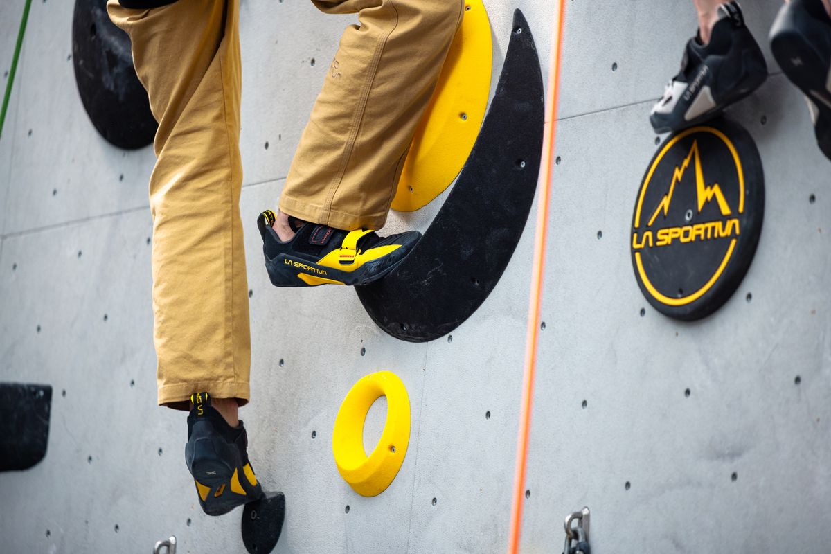 Kletterschuh HyperEZ auf einem Tritt an der Wand einer Kletterhalle, daneben das Seil