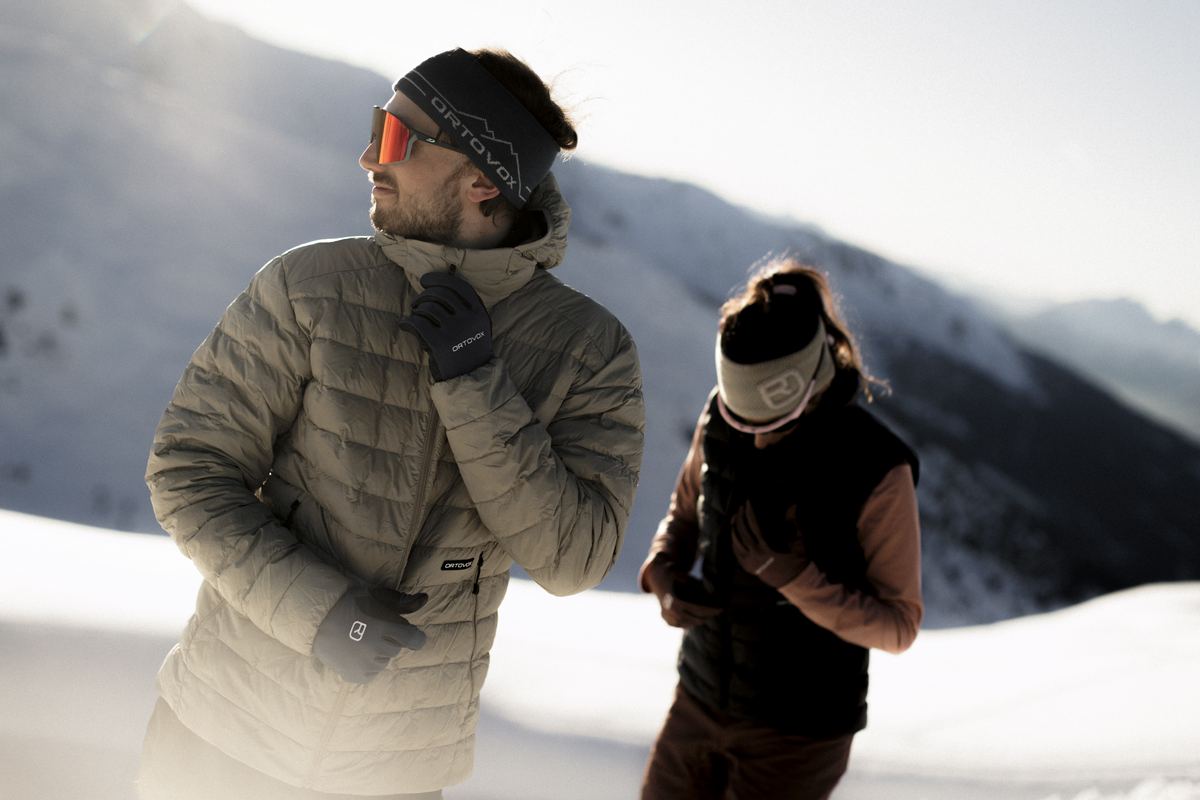 Skitourengeher in einer Daunenjacke von Ortovox und Begleiterin in einer Weste auf einem Bergr&uuml;cken