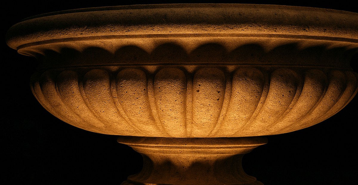 Bodenstrahler setzt Streiflicht auf die profilierte Schale eines Barock Springbrunnens und hebt das Relief hervor
