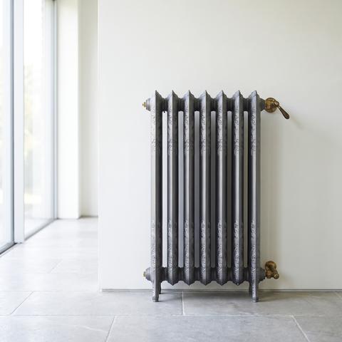 Bad Heizkörper in Dunkelgrau im Barockstil an der hellen Wand
