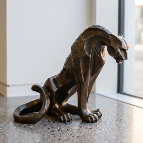 Modern bronze sculpture of a panther in a stretched pose