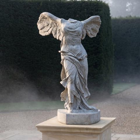 Stone garden sculpture of a winged victory on a base