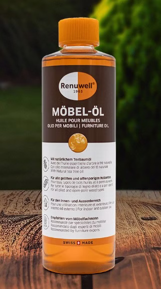 Renuwell Möbel-Öl 500 ml mit natürlichem Teebaumöl in einer transparenten Flasche mit orangefarbenem Verschluss auf einer Holzoberfläche.