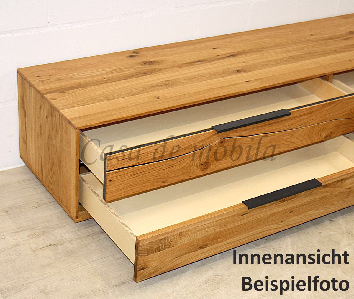 Offene Schubladen mit langen dunklen Griffen Zwei offene Holzschubladen mit langen dunklen Griffen unter einer gemaserten Deckplatte.