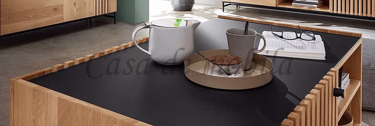 Tassen auf dunkler Glasdeckplatte Dunkle Glasdeckplatte eines Holz-Couchtischs mit Tassen und hellem Tablett.