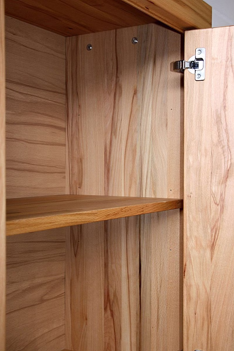Innenfach mit Holzfachboden und Scharnier Holz-Innenfach eines Schranks mit Einlegeboden und Metallscharnier an der geöffneten Tür.