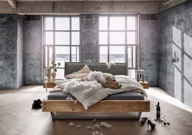 TPT WOODSTOCK 620 Balkenbett aus Wildeiche mit Polsterkopfteil und Metallkufe im Wohnambiente Balkenbett WOODSTOCK 620 von TPT aus massiver Wildeiche mit Doppelzapfen, grauem Polsterkopfteil und Metallkufe im modernen Schlafzimmer