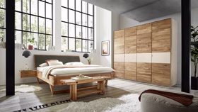 schlafzimmer-holzbett-woodstock-620-anthrazit-rustikal. Rustikales Balkenholzbett WOODSTOCK 620 mit anthrazitfarbenem Kopfteil in einem modern eingerichteten Schlafzimmer.