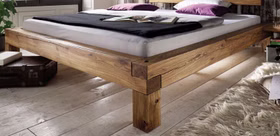 WOODSTOCK – Bettgestell mit Holzbein Rustikales Holzbett mit kräftigen Balken und sichtbarer Eckverbindung an einem geraden Holzbein.