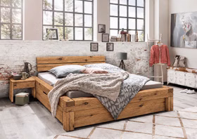 WOODSTOCK I – Schubladenbett Rustikales Holzdoppelbett mit kräftiger Maserung und integrierten unteren Schubladen in einem hellen Schlafzimmer.