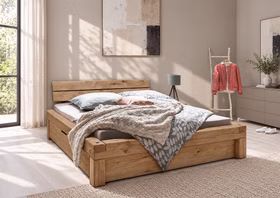 WOODSTOCK I – Schubladenbett Rustikales Holzdoppelbett mit kräftiger Maserung und integrierten unteren Schubladen in einem hellen Schlafzimmer.