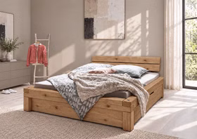 WOODSTOCK I – Schubladenbett Rustikales Holzdoppelbett mit kräftiger Maserung und integrierten unteren Schubladen in einem hellen Schlafzimmer.